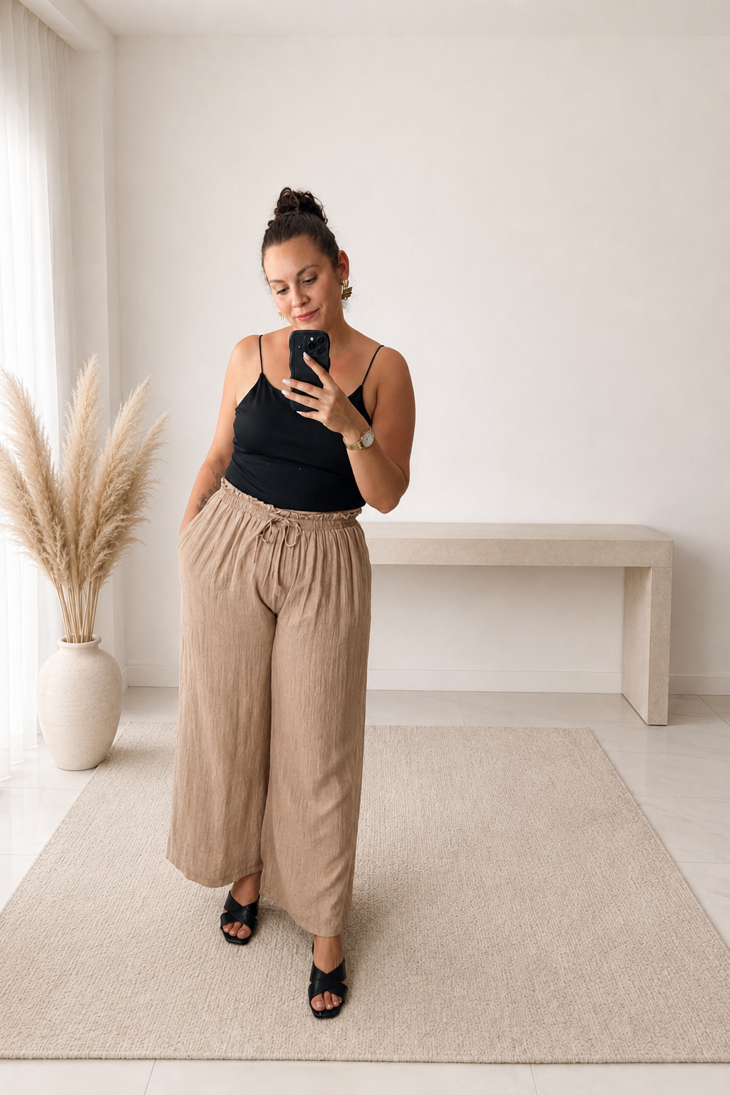 Pantalon Riviera beige à jambes larges et taille élastiquée porté avec un débardeur noir