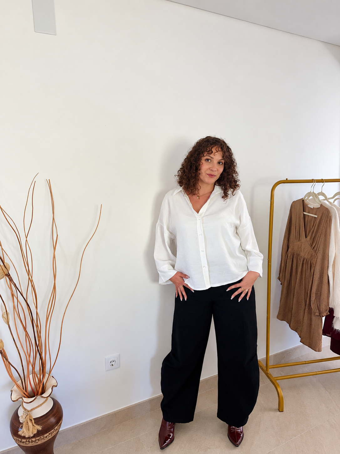 Chemise Melia blanche oversize portée de face, sortie sur un pantalon noir, avec les manches retroussées.