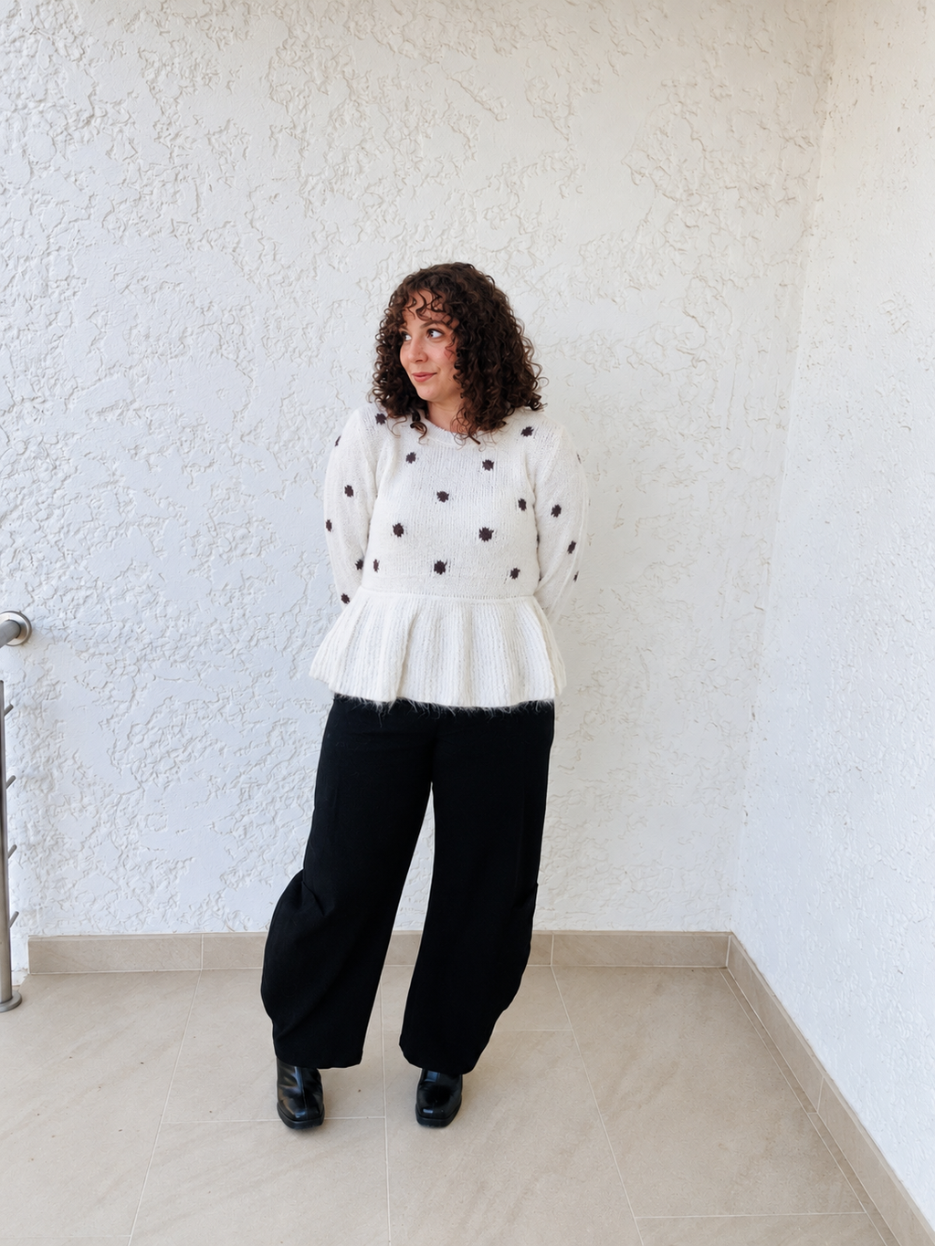 Pull Rosalie à pois porté avec un pantalon noir, silhouette entière en extérieur.