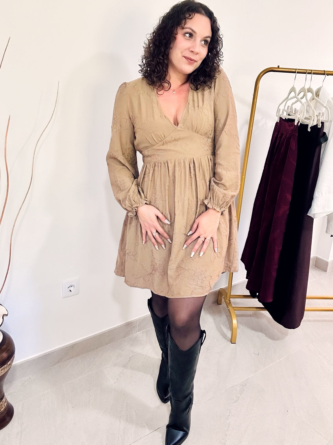 Robe courte Romy taupe à motifs floraux ton sur ton, portée de face avec des collants et des bottes noires.