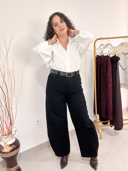 Jean Allie noir à coupe ample, porté avec une ceinture et une chemise blanche, vue de face en pied.