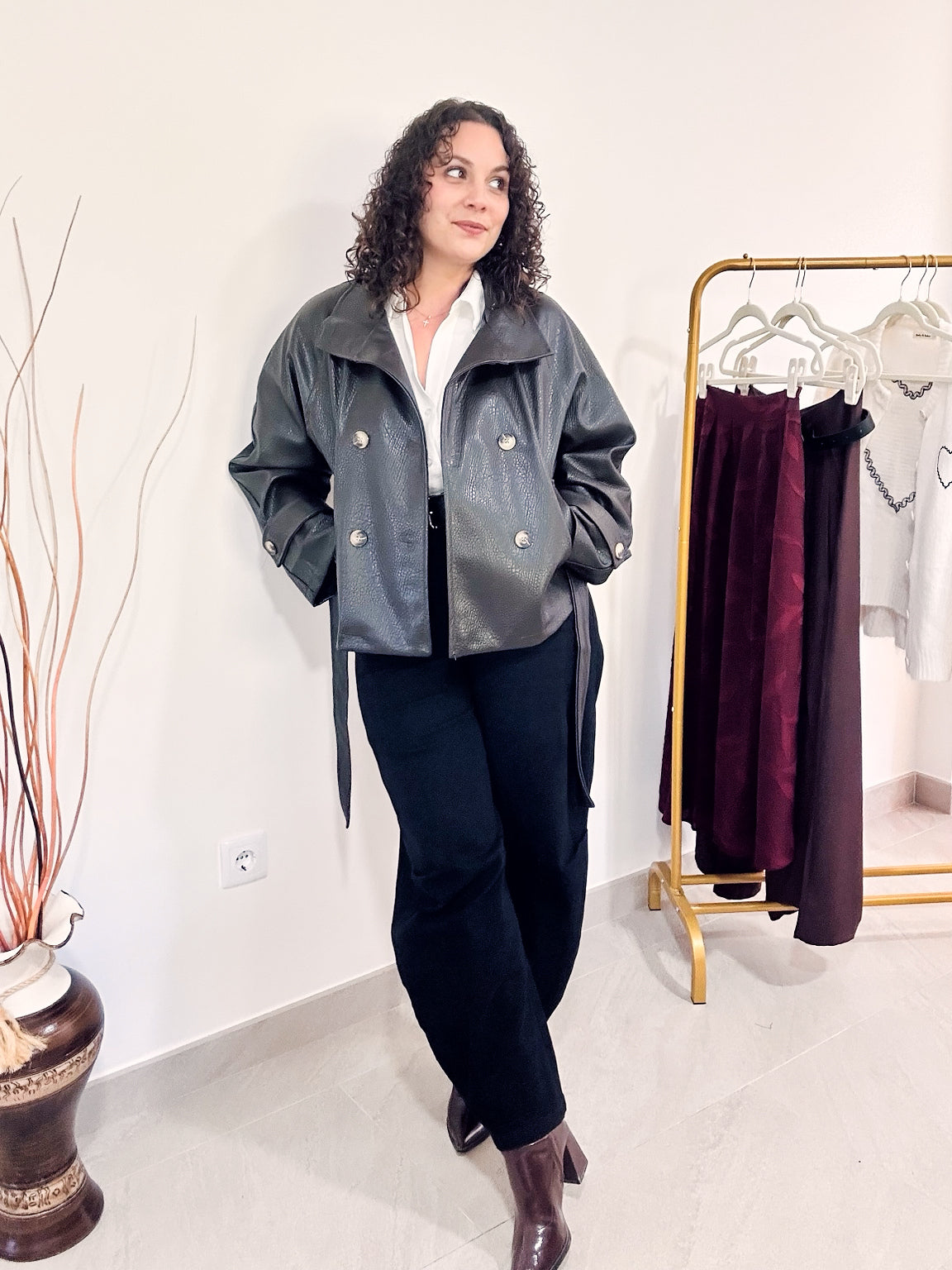Veste Noelle en simili cuir marron portée ouverte avec une chemise blanche et un pantalon noir, en intérieur.