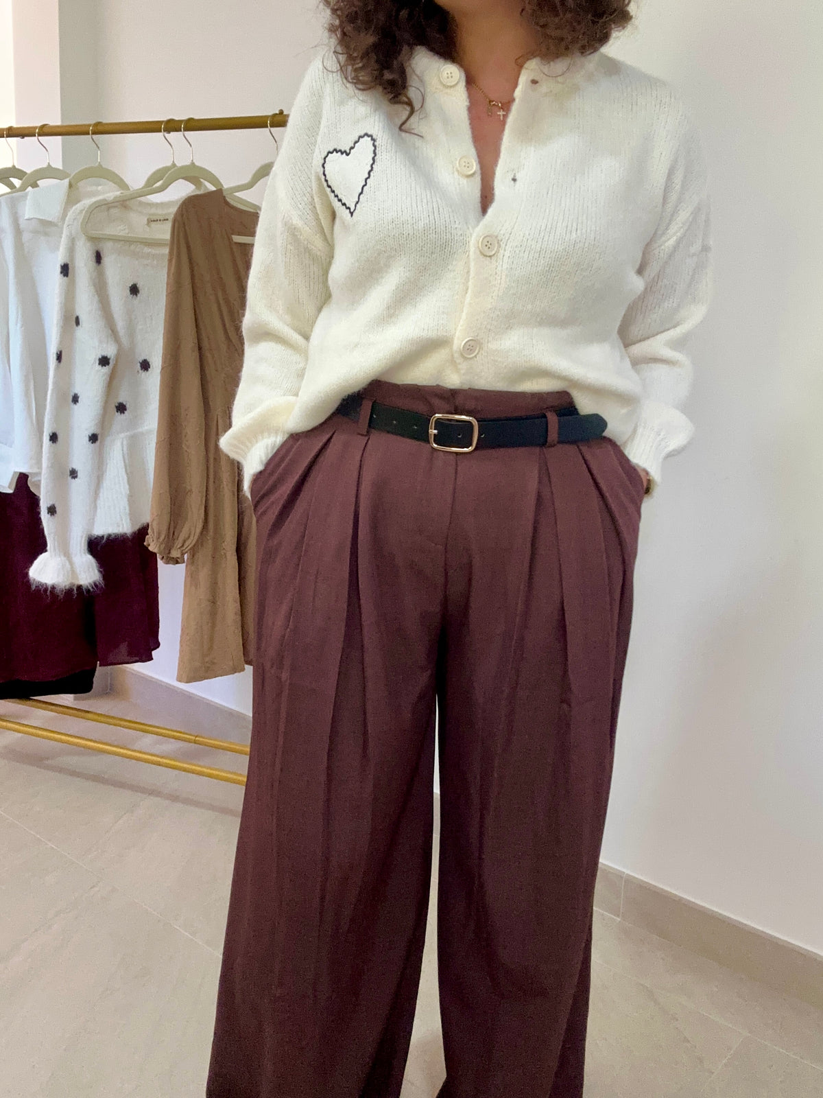Vue de face du pantalon Livia marron, avec les mains dans les poches et une chemise blanche rentrée à la taille.